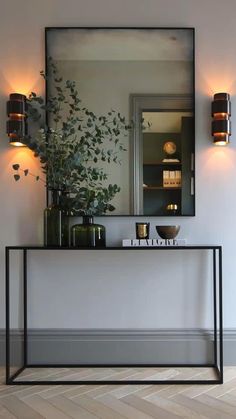 a mirror and some plants on a shelf in a room with white walls, wood floors and flooring