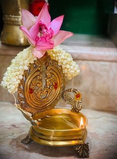 a gold vase with flowers in it sitting on a table