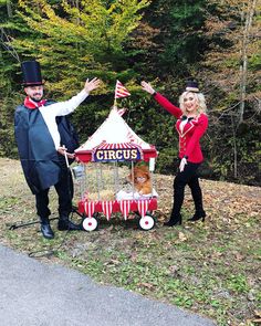 two people dressed in circus costumes standing next to a carnival tent