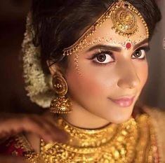 a woman wearing gold jewelry and makeup