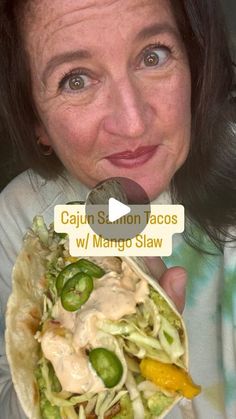 a woman holding a taco in her right hand and looking up at the camera