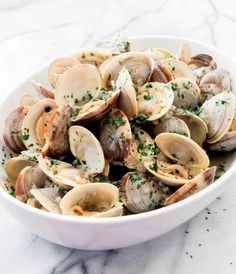 a white bowl filled with clams and garnished with parsley on top