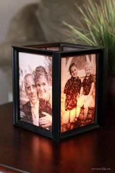 an old photo is lit up in a small box on a table next to a potted plant