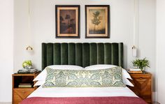 a bed with green headboard and two pictures above it