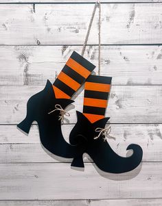 a pair of black and orange striped socks hanging from a string on a white wooden wall