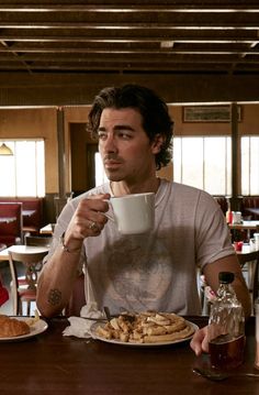 a man sitting at a table with a plate of food and drink in front of him