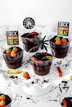 halloween desserts are arranged in small bowls on a white table with candy and candies