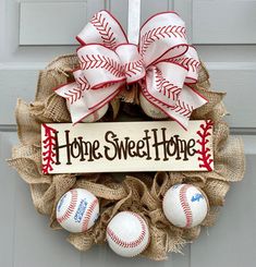 a wreath with baseballs on it and a sign that says home sweet home hanging from the front door