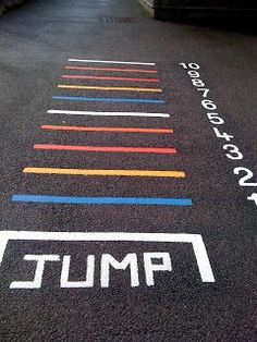 an empty parking lot with colorful lines painted on the ground and white writing that says jump