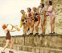 a group of women standing on top of a stone wall next to each other holding musical instruments