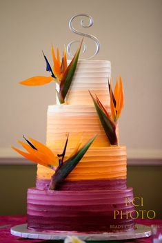 a multi - layered cake with birds of paradise on top is decorated in pink, orange and yellow