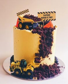 a construction themed cake with dump trucks and dirt on the bottom, sitting on a plate