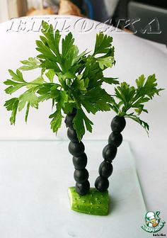 there is a small plant made out of black beads on a white tablecloth with a dog in the background