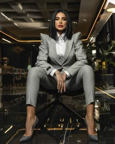 a woman sitting on top of a chair in a suit