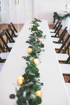 the long table is decorated with candles and greenery