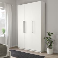 a bedroom with white furniture and a potted plant