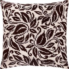 a brown and white pillow with an abstract design on the front, sitting against a green background