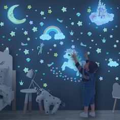 a little boy that is standing in front of a wall with some stars and unicorns on it