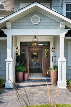 the front entrance to a house with potted plants