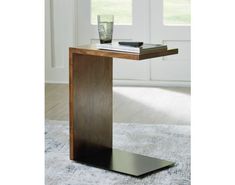 a wooden table with a glass and book on it in front of a window next to a rug