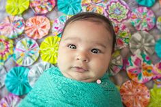 a baby wrapped in a blanket with colorful paper flowers