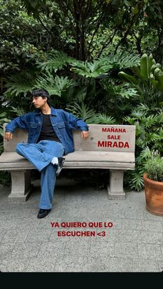 a man sitting on top of a cement bench next to green plants and potted trees