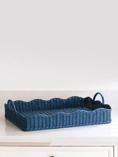 a blue wicker tray sitting on top of a white counter next to a drawer