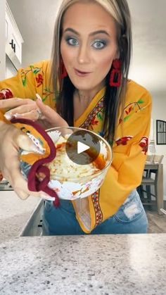 a woman holding a bowl with food in it and looking at the camera while making a face