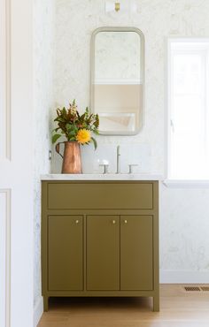 a bathroom with a sink, mirror and flowers on the counter