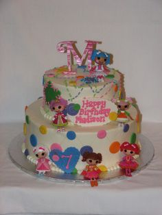 a three tiered birthday cake decorated with cartoon characters and the letter m on top