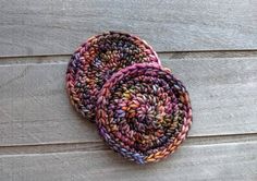 two crocheted coasters sitting on top of a wooden table