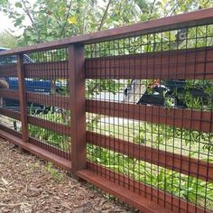 the fence is made of metal wire and has green plants growing on it, along with grass