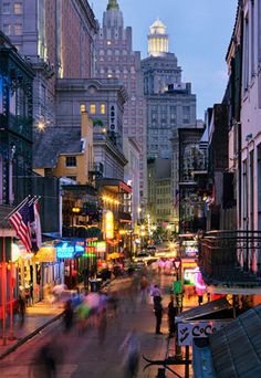 people are walking down the street in an urban area at dusk with tall buildings on either side