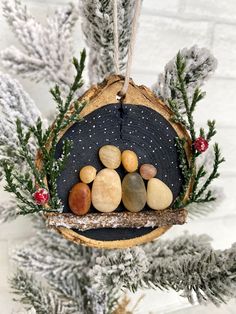 a wooden ornament with rocks and pine needles hanging from it's side