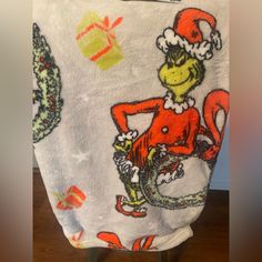 the grinch is wearing a santa hat and holding onto a white towel that has an image of a lizard on it