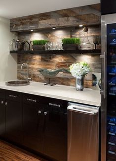 a kitchen with wooden walls and stainless steel appliances in the center, along with shelves filled with wine bottles