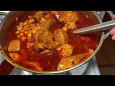 a pot full of stew with meat and vegetables being stirred by a ladle on the stove