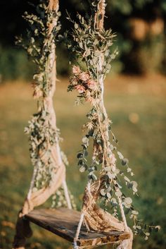 an old wooden bench with some flowers hanging from it's sides and tied to the back