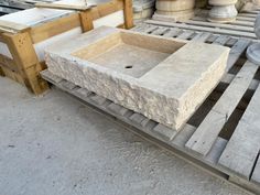 a stone sink sitting on top of pallets in a room filled with cement blocks