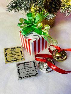 a small gift box with a red ribbon tied around it next to a christmas ornament