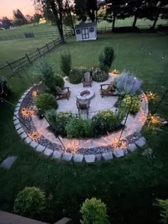 an outdoor fire pit surrounded by rocks and lights in the middle of a grassy area