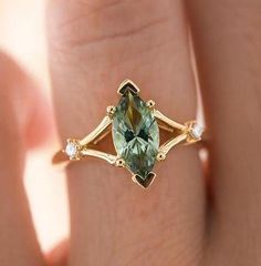 a woman's hand with a ring that has an oval green stone in it