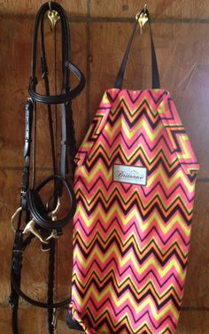 a horse's bridle is next to a pink and yellow chevroned bag