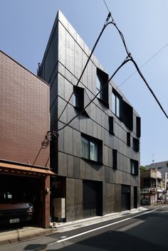 the building is made out of wood and has many windows on each side, as well as two cars parked in front of it