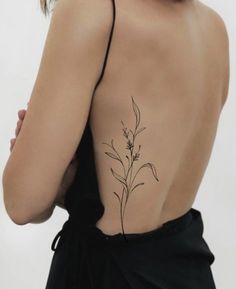 the back of a woman's body with a tattoo on her left shoulder and an image of a plant