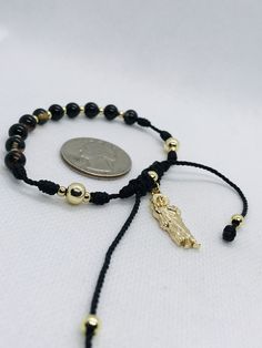 "Handmade St. Judas Thaddeus bracelet with natural nazar boncuk stone beads known as Turkish eye for protection and evil eye. 10 nazar boncuk beads as Ave Maria for a rosary, 2 mistery and plated gold beads as Our Father. Adjustable from 7''inches up to 9''inches. Material: Natural Agate stone beads Black/Brown 6mm Plated gold beads 6mm, 4mm, 3mm St. Judas Thaddeus pendant 2.50cm Black string #9 Pulsera de San Judas Tadeo hecha a mano con bolas de piedra natural nazar boncuk conocido como el ojo Gold Beaded Rosary Bracelet For Healing, Adjustable Spiritual Rosary Bracelet With Polished Beads, Spiritual Gold Beads Bracelets, Spiritual Gold Beaded Bracelet With Black Beads, Spiritual Rosary Bracelet With Gold Beads As Gift, Spiritual Gold Beads Rosary Bracelet Gift, Gold Hand-strung Rosary Bracelet For Healing, Gold Rosary Bracelet With Black Beads As Gift, Adjustable Rosary Bracelet With Gold Beads As Gift