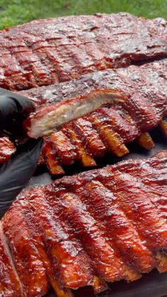 someone in black gloves is cutting up some ribs