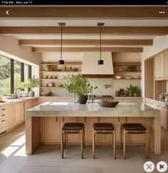 a large kitchen with wooden cabinets and counter tops, along with two stools in front of the island