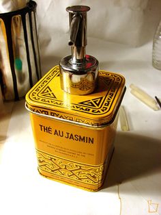 a yellow tin with the word the au jasmin on it sitting next to other items