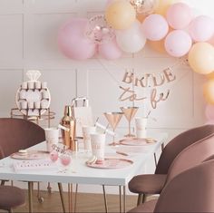 a white table topped with lots of pink and gold balloons